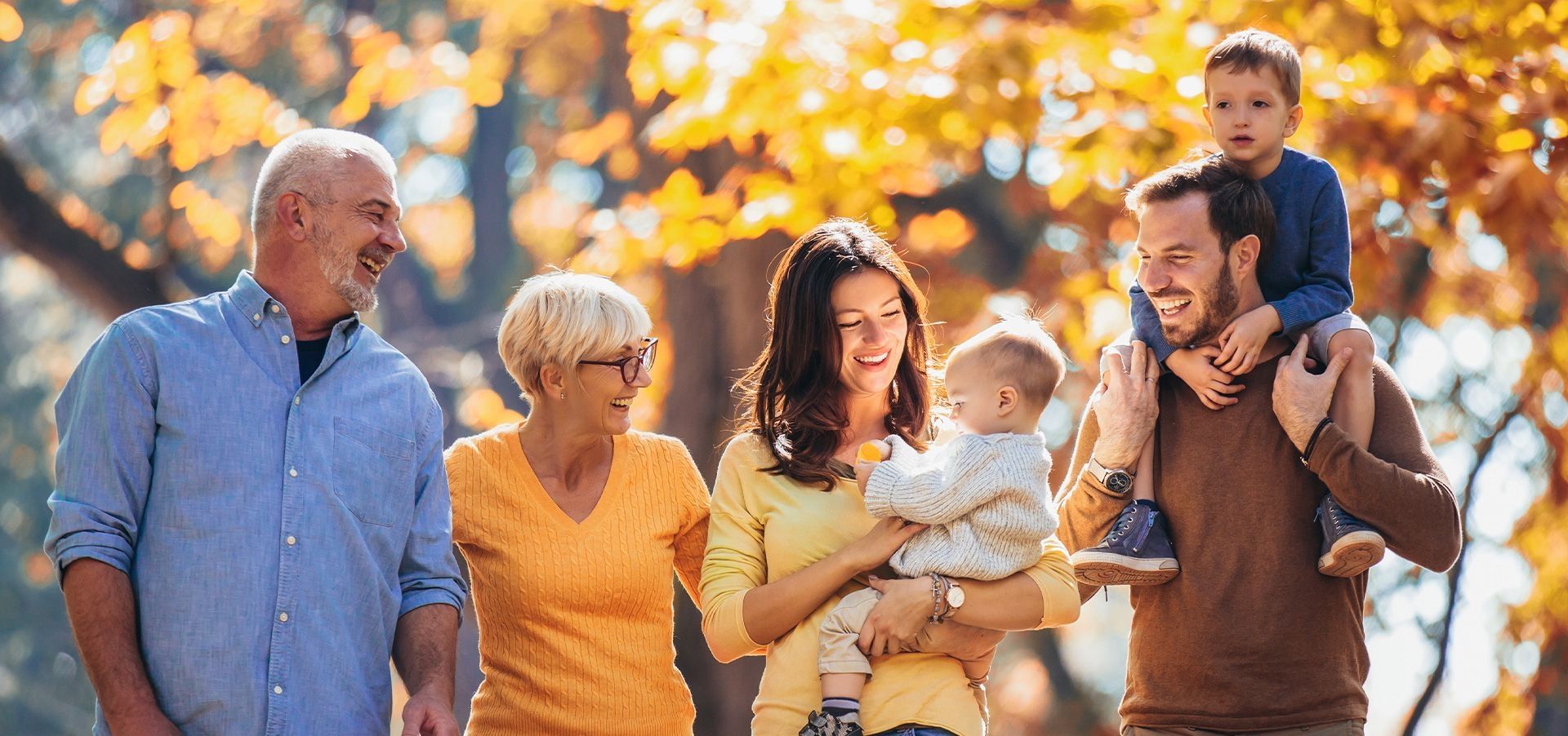 Eine glückliche Familie mit Herbstlaub im Hintergrund